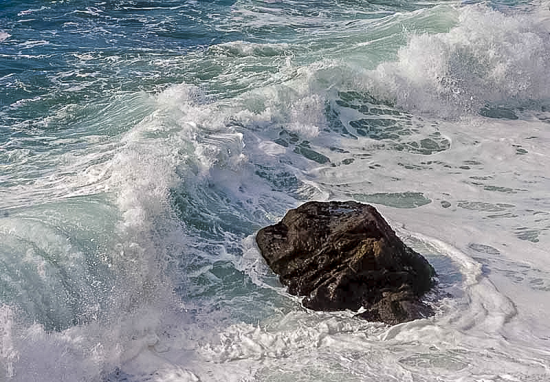 An ocean wave about to break over a rock.